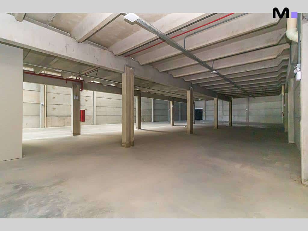 Espaço amplo e vazio no ABC Business Park com colunas de concreto e teto industrial.