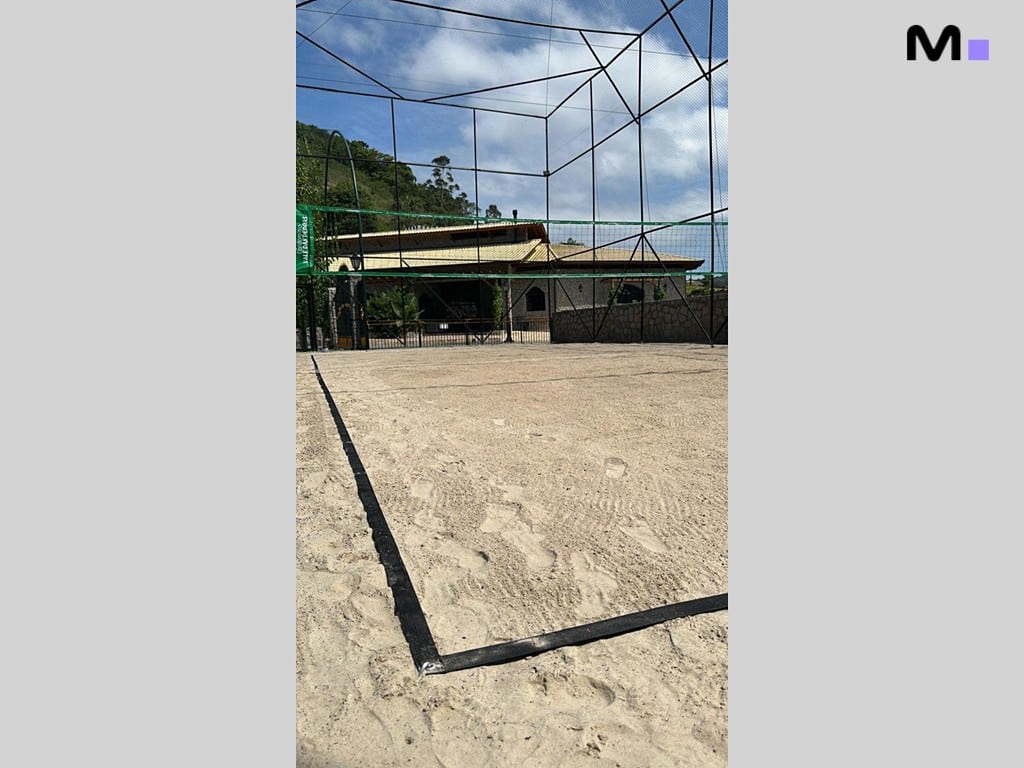 Quadra de areia no Condomínio Vale das Pedras, com rede e marcações pretas.