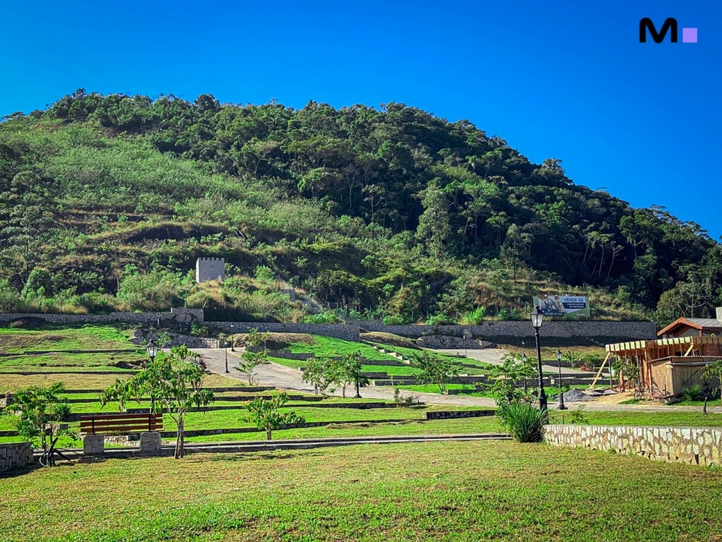 Vista do Condomínio Vale das Pedras, com área verde, montanha e céu azul. Lazer e natureza!