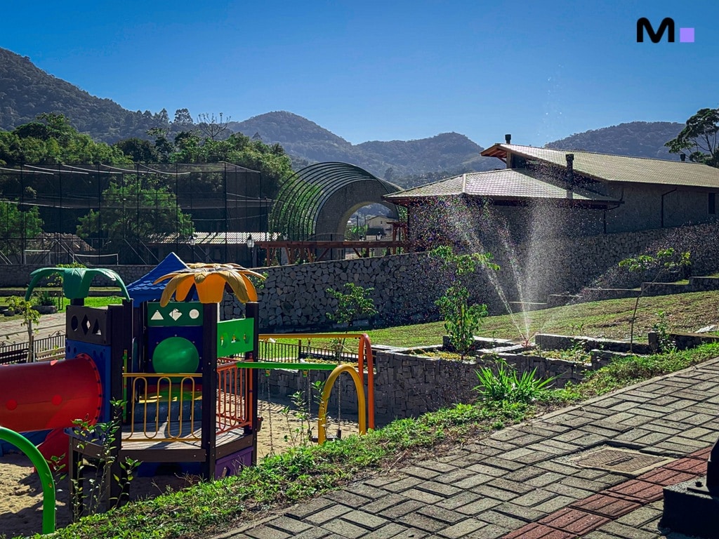 Parque infantil no Condomínio Vale das Pedras com montanhas ao fundo.