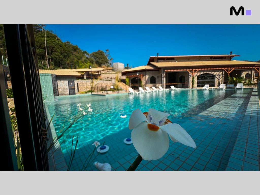 Piscina cristalina no Condomínio Vale das Pedras, com flor branca em primeiro plano.