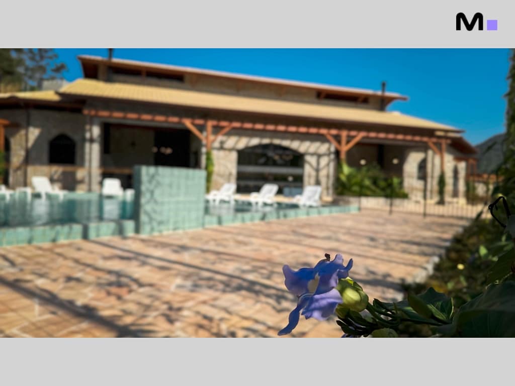 Casa no Condomínio Vale das Pedras com piscina e flor azul em primeiro plano.