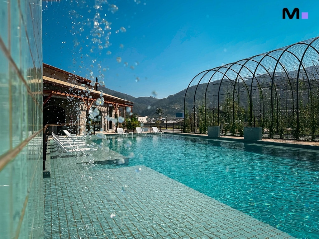 Piscina azul do Condomínio Vale das Pedras em dia ensolarado.