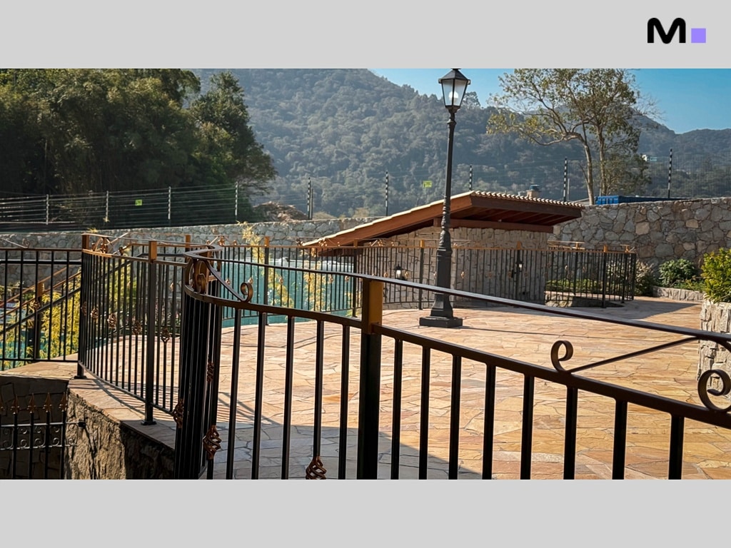 Paisagem do Condomínio Vale das Pedras com área de lazer e montanhas ao fundo.