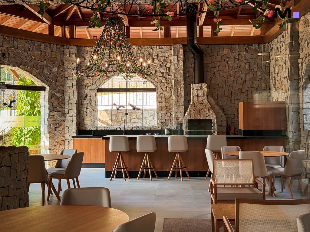 Interior rústico com churrasqueira e decoração floral no Condomínio Vale das Pedras.