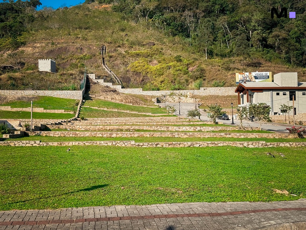 Vista do Condomínio Vale das Pedras com gramado, escadaria e vegetação exuberante.