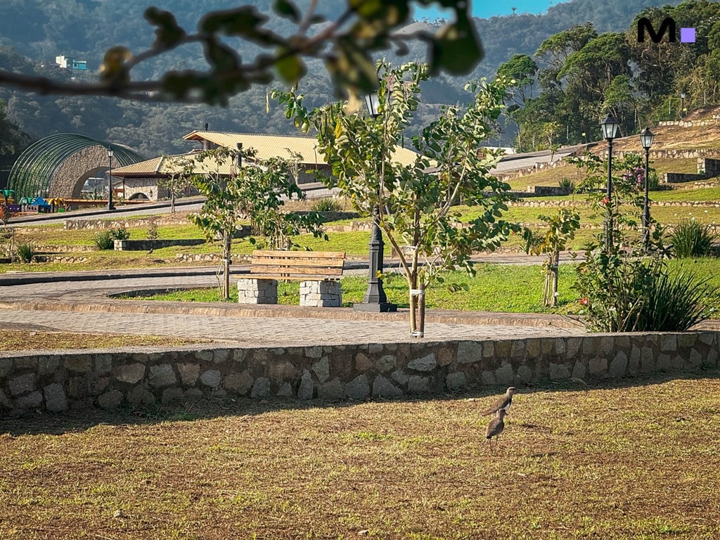 Banco de parque no Condomínio Vale das Pedras com área verde e paisagem montanhosa.