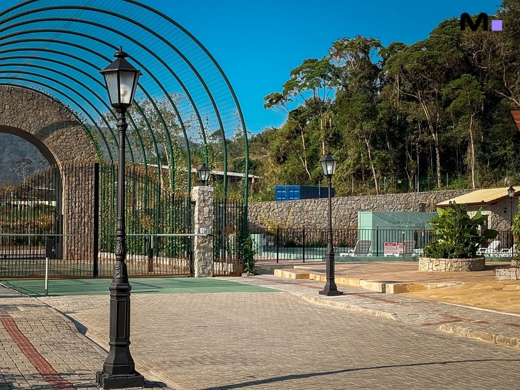 Entrada do Condomínio Vale das Pedras com portão de pedra, iluminação e paisagismo.