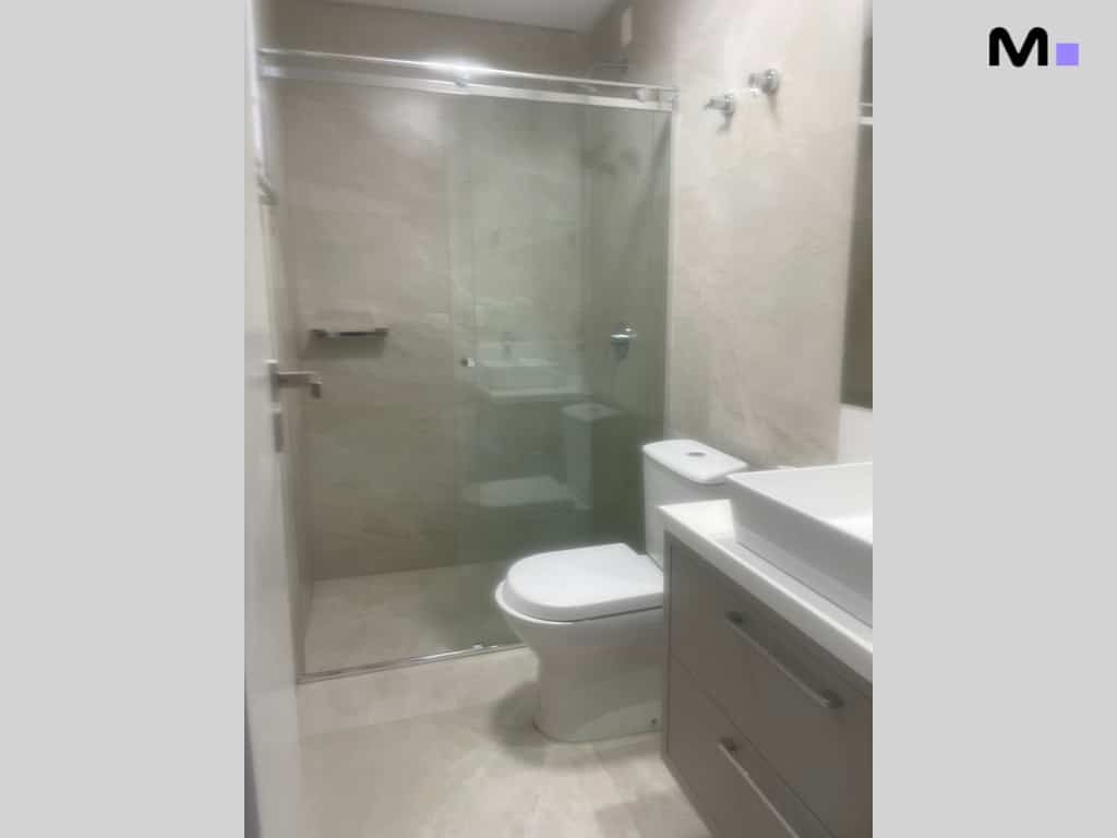 Banheiro moderno com box de vidro e pia branca, Condomínio House Haras.