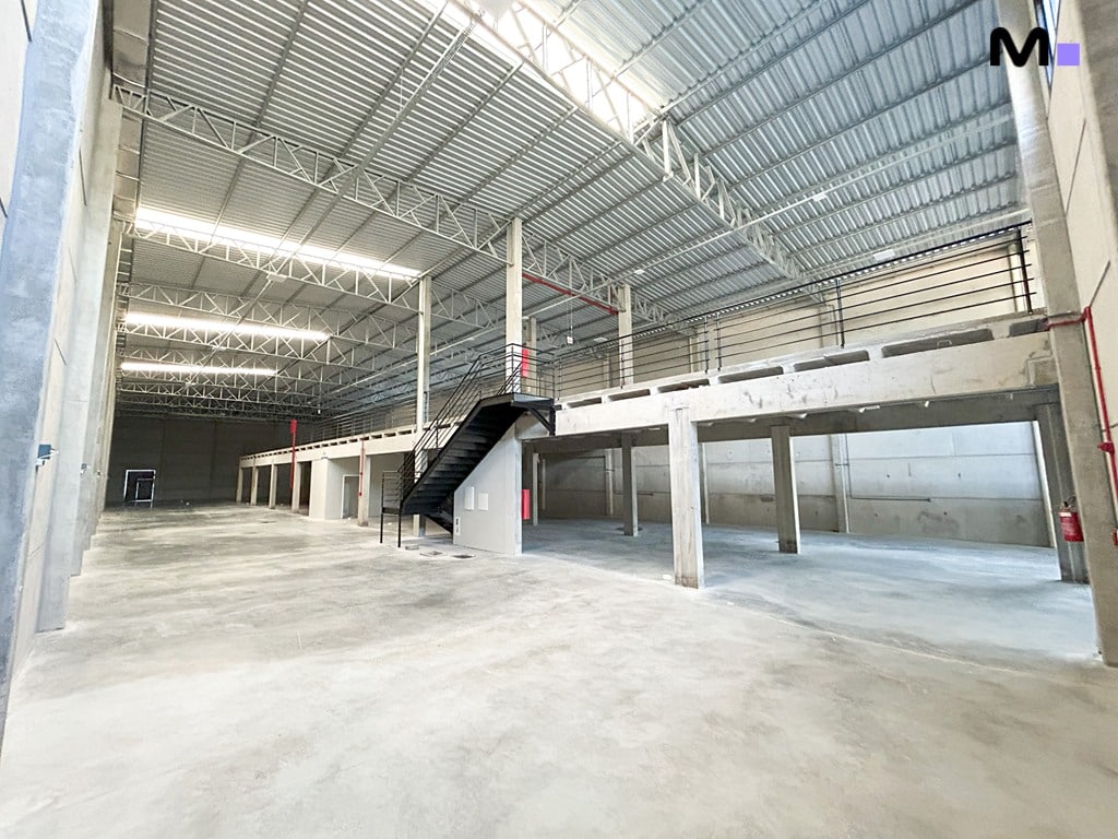 Interior espaçoso de armazém no ABC Business Park com mezanino e estrutura metálica no teto.
