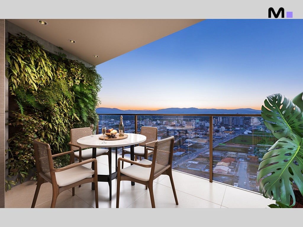 Varanda do Quest Residence com mesa, cadeiras, parede verde e vista da cidade.