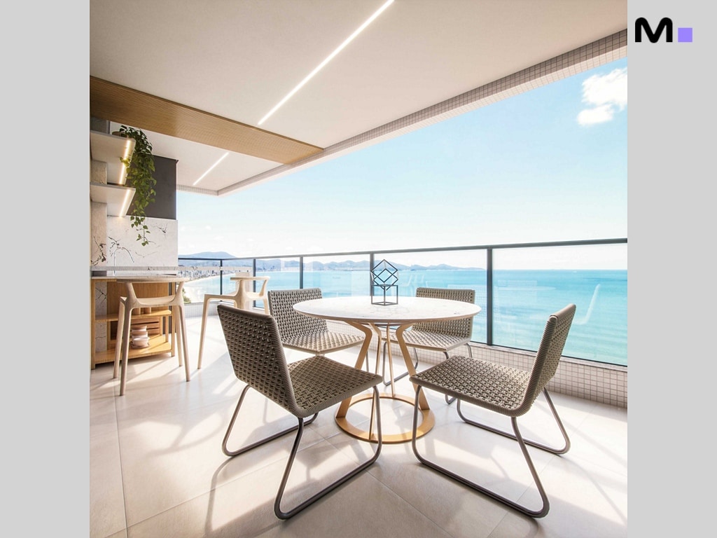 Varanda do Hudson Park Residence com mesa, cadeiras e vista para o mar.