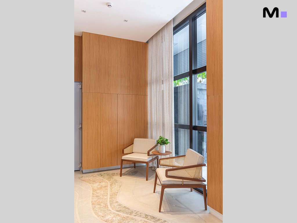 Hall de entrada da Vila Aurora Residence com cadeiras de madeira e janela ampla.