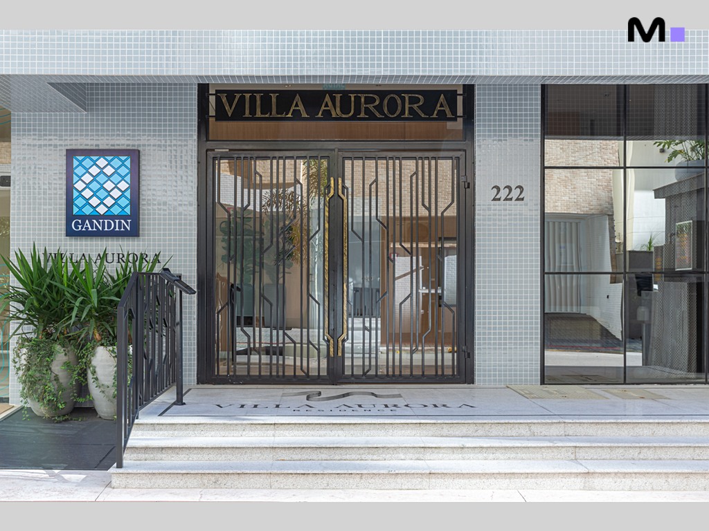 Entrada do Vila Aurora Residence, com porta de ferro e detalhe do nome "Vila Aurora".