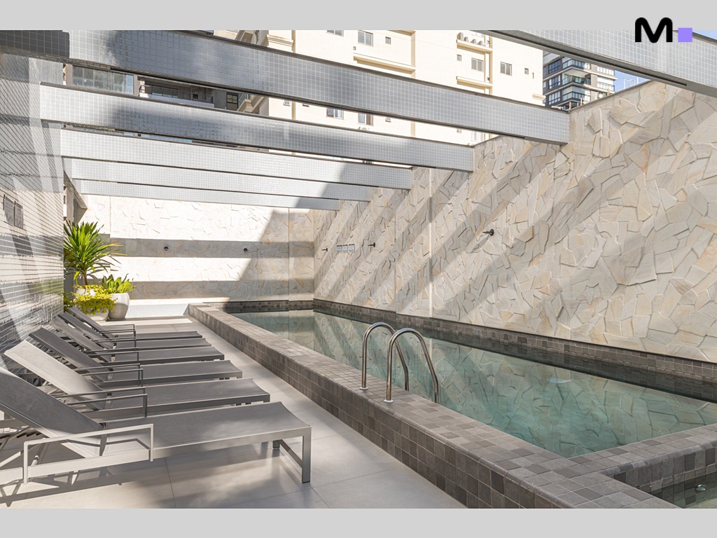 Piscina moderna na Vila Aurora Residence com espreguiçadeiras e revestimento de pedra natural.