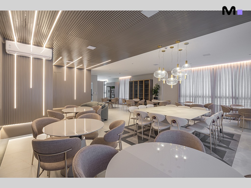 Interior moderno e iluminado do Vila Aurora Residence com mesas e cadeiras elegantes.