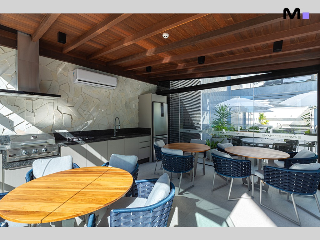 Cozinha gourmet moderna no Vila Aurora Residence com churrasqueira e área de refeições iluminada.