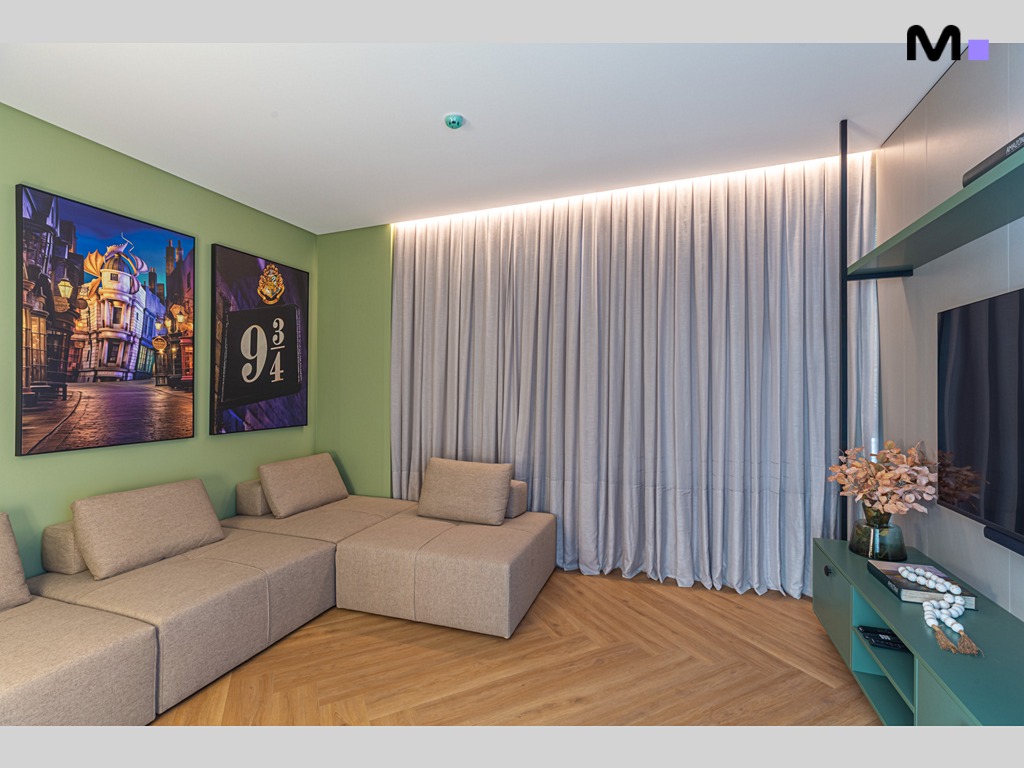Sala de estar moderna da Vila Aurora Residence com sofá modular bege e decoração temática.