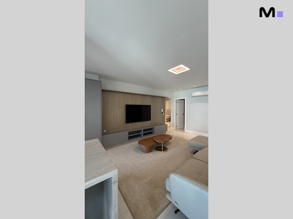 Sala de estar moderna no Garden Square Residence com TV e sofá de couro.