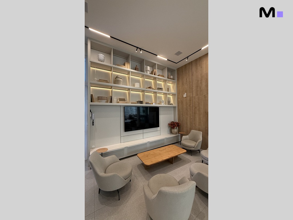 Sala de estar moderna no Garden Square Residence com estante iluminada, poltronas e mesa de centro.