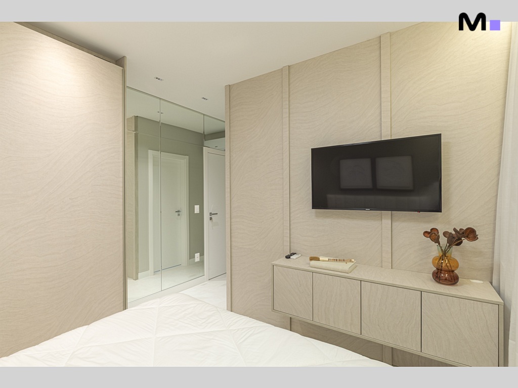Quarto moderno com TV, armário espelhado e cama branca. Design Vila Aurora Residence.