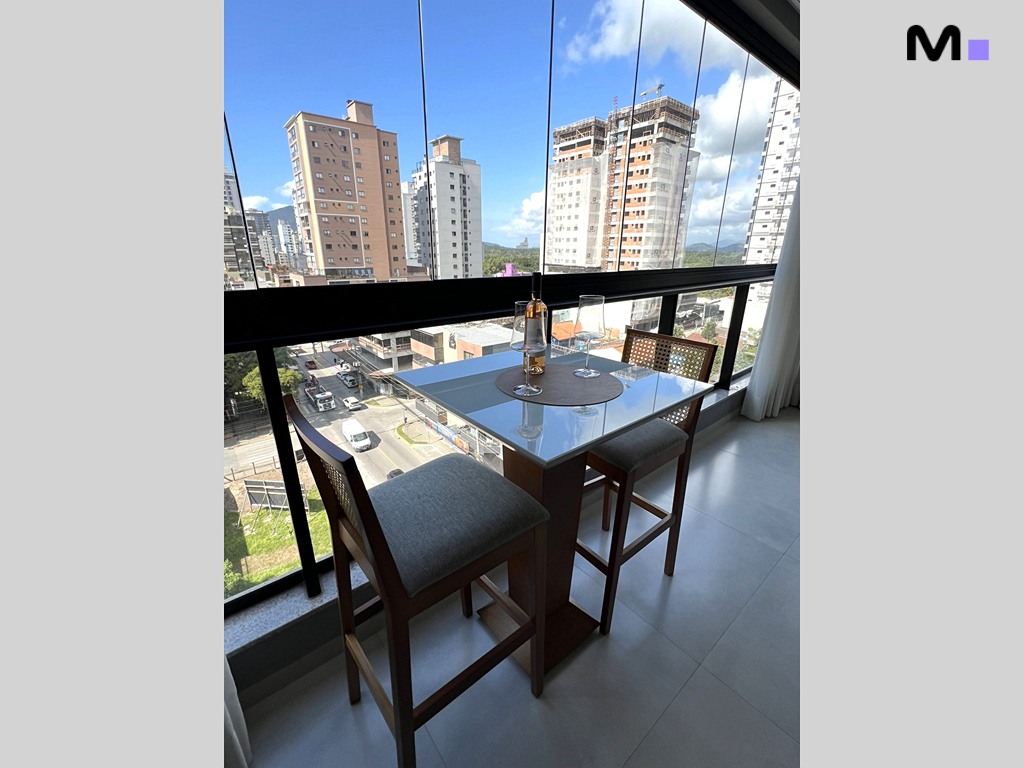 Mesa alta com vinho e cadeiras na varanda do Realta Residence, com vista para a cidade.