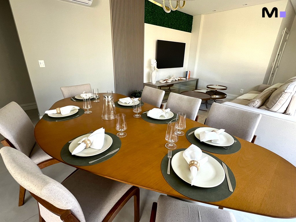 Mesa de jantar oval de madeira com cadeiras estofadas e decoração moderna no Realta Residence.