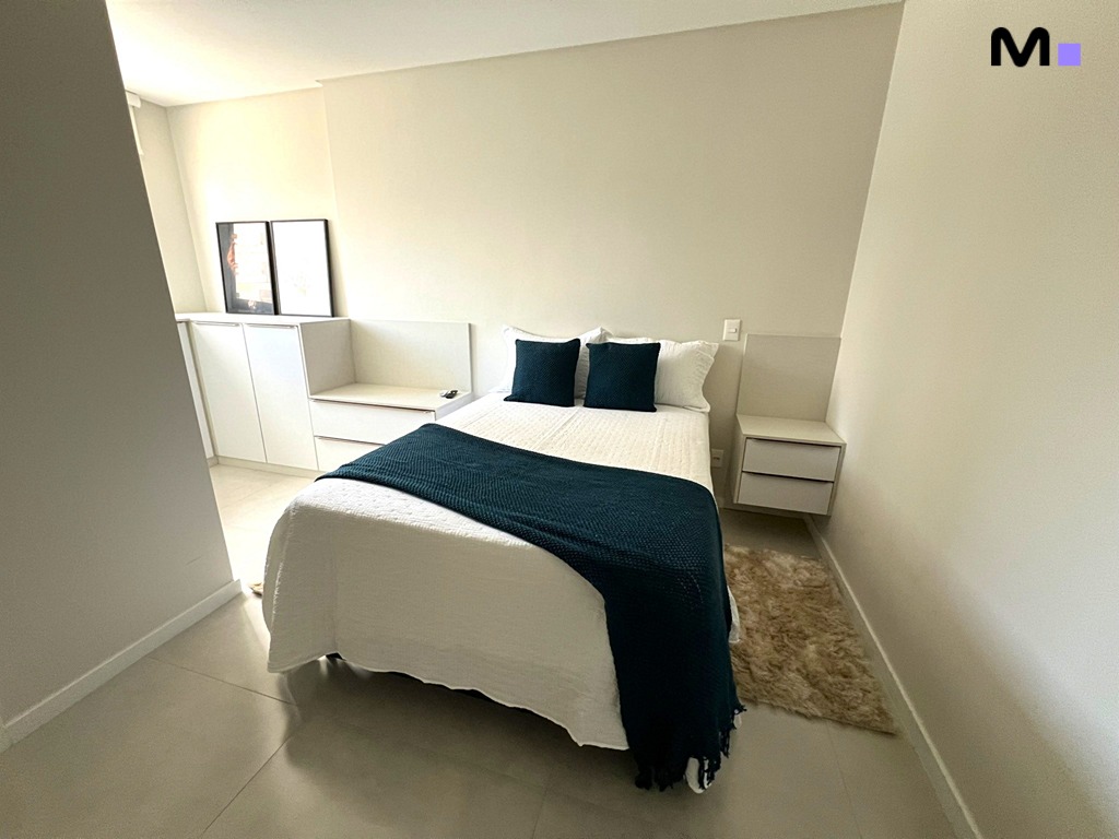 Quarto aconchegante no Realta Residence com cama, roupa de cama branca e manta verde escura.