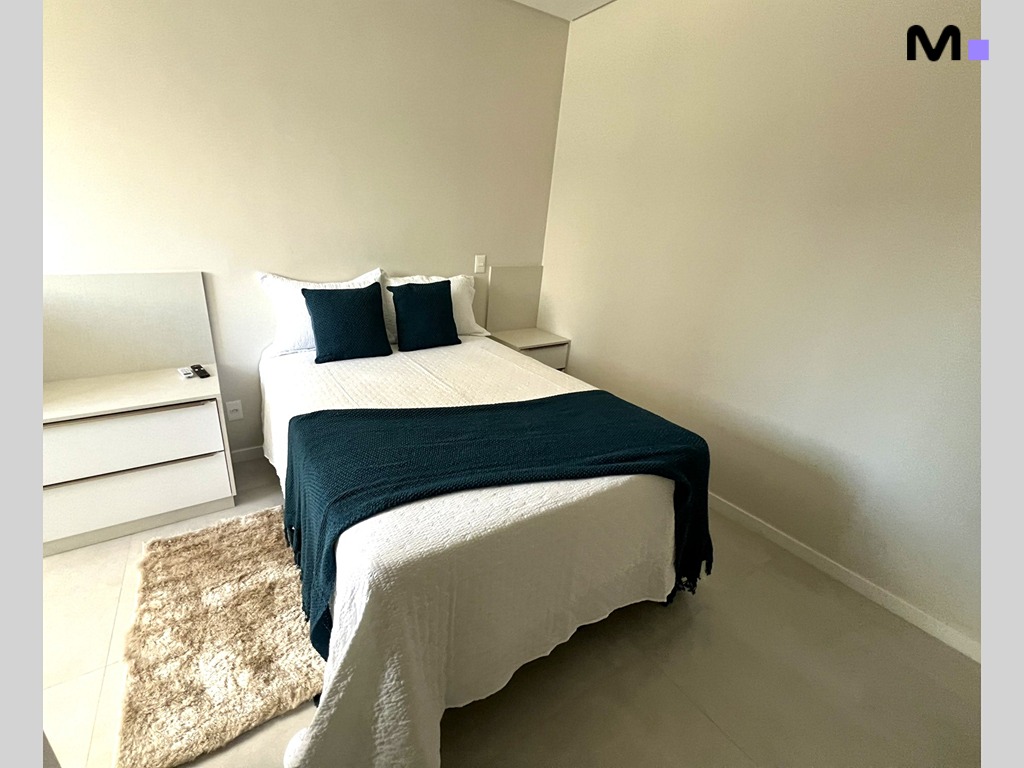 Quarto aconchegante no Realta Residence: cama com manta azul e decoração minimalista.