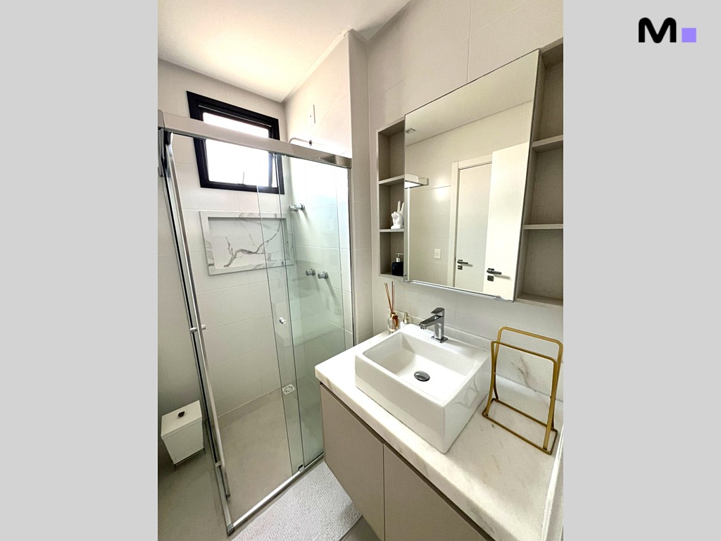 Banheiro moderno da Realta Residence com pia branca, espelho e box de vidro.