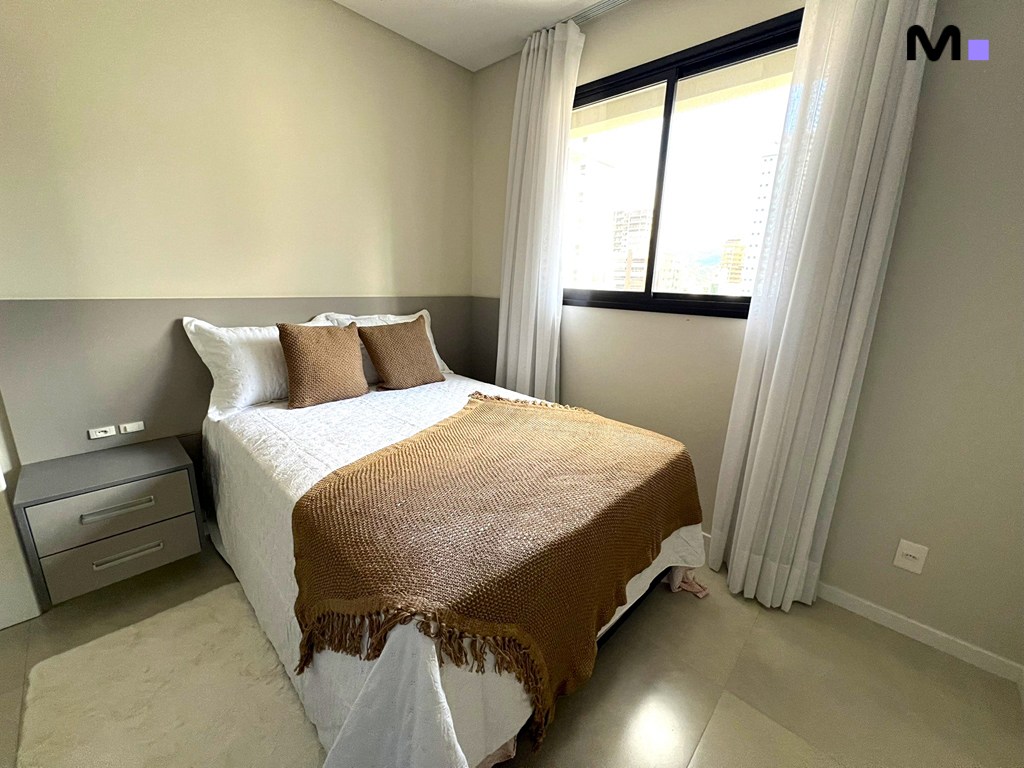 Quarto aconchegante no Realta Residence com cama, roupa de cama marrom e janela iluminada.