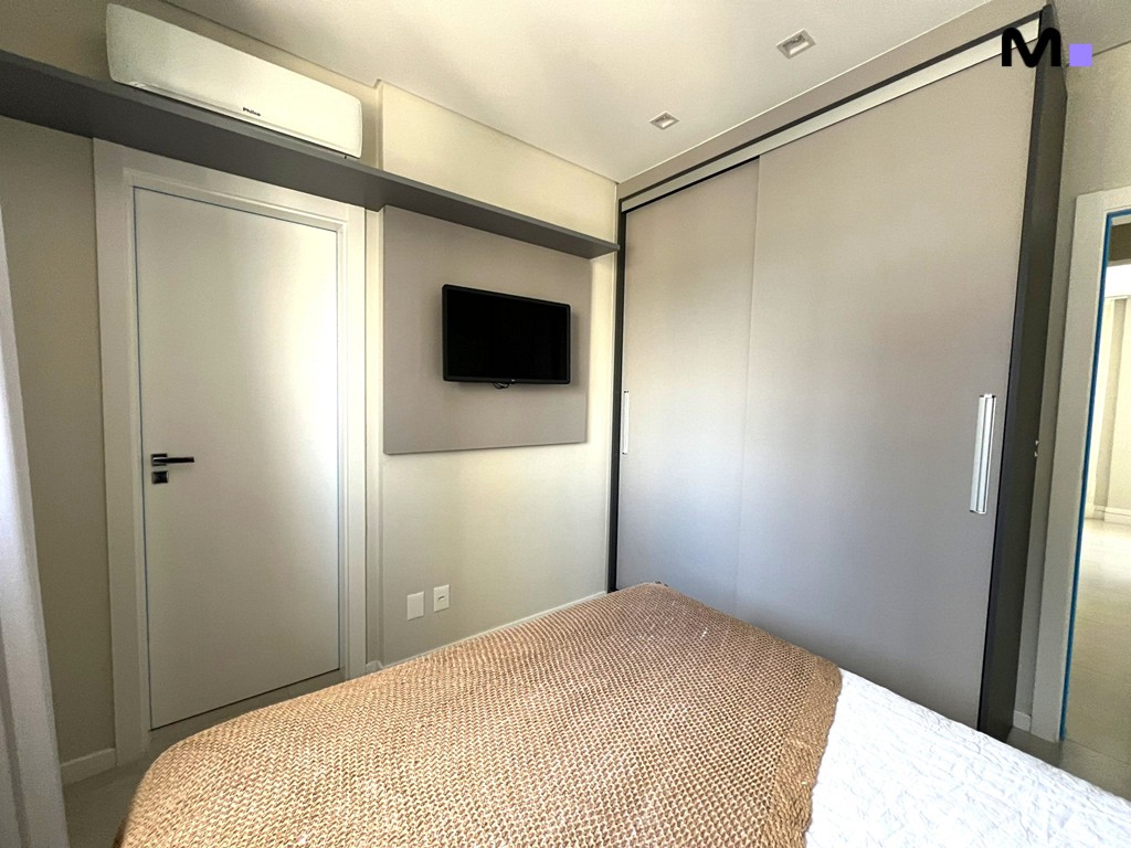 Quarto moderno com cama, TV e armário embutido, parte do Realta Residence.