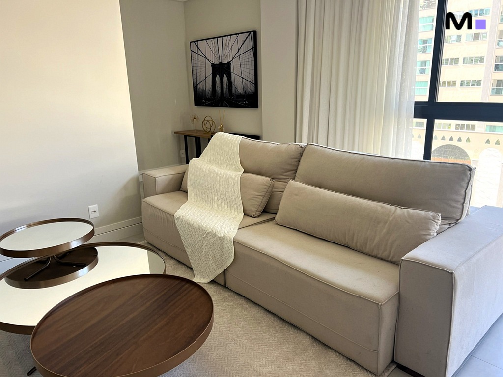 Sala de estar moderna no Realta Residence com sofá bege, mesa de centro e decoração minimalista.