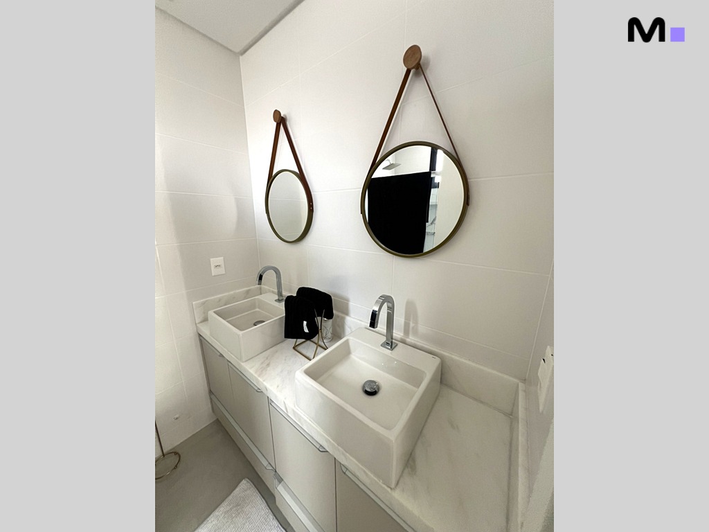 Banheiro moderno com duas pias quadradas e espelhos redondos pendurados. Realta Residence.