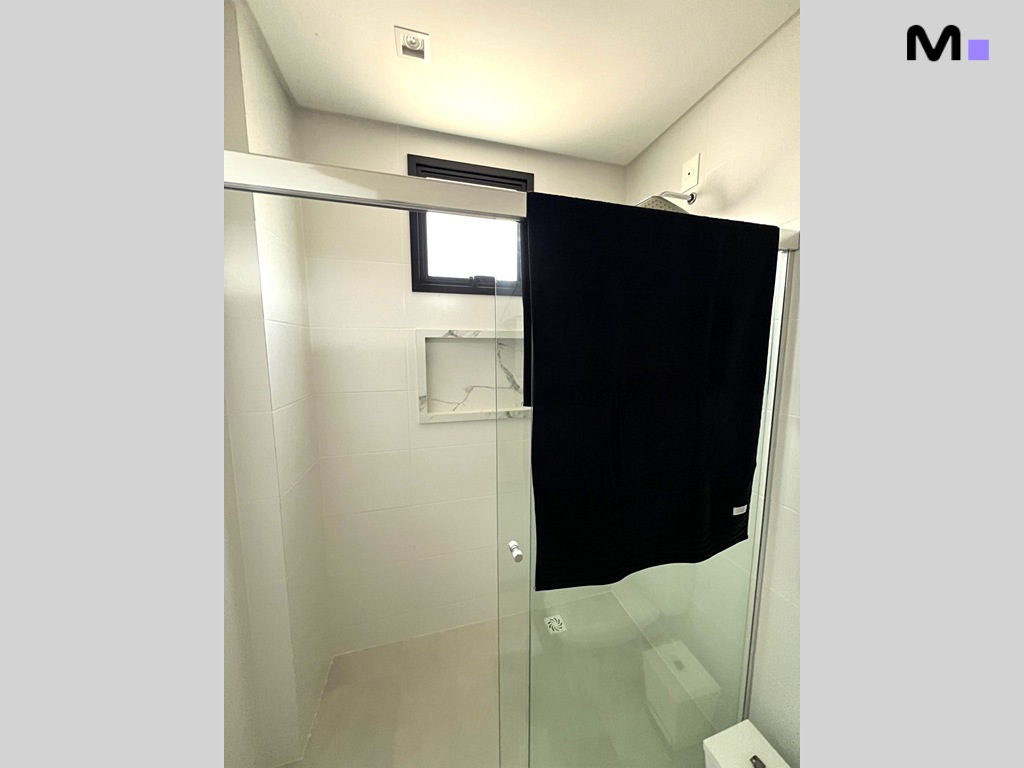 Banheiro moderno com box de vidro e toalha preta pendurada. Residência Realta.
