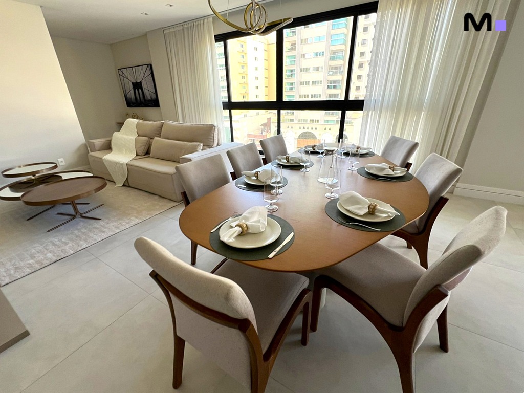 Sala de jantar moderna no Realta Residence, com mesa oval e cadeiras elegantes. Iluminação natural e decoração sofisticada.