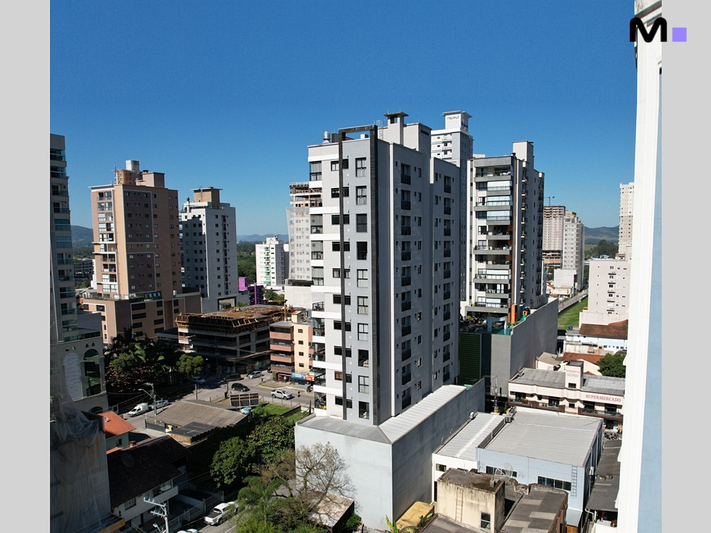 Vista urbana com edifícios altos e céu azul. Realta Residence ao fundo.