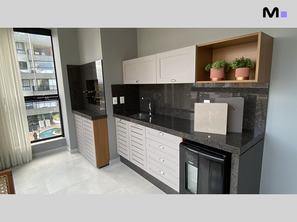 Cozinha moderna da Realta Residence com armários claros, pia e frigobar. Detalhes em madeira e granito escuro.