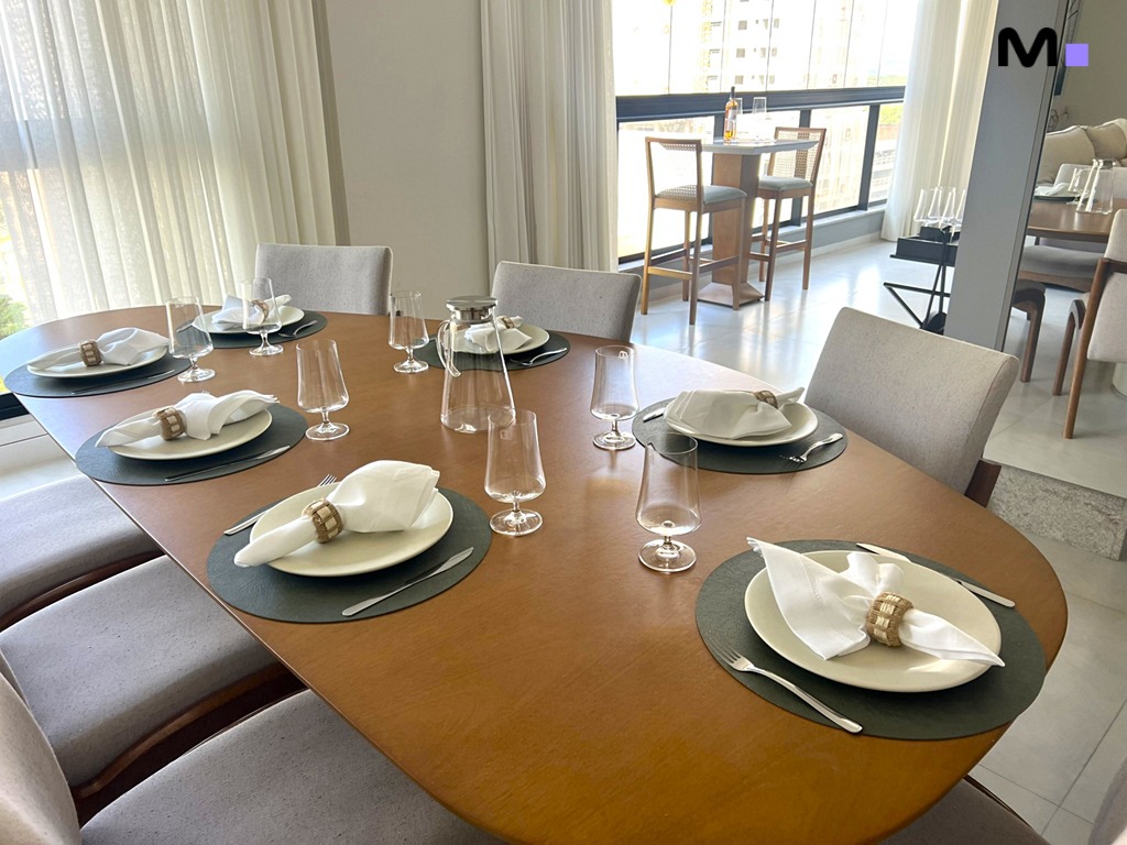Mesa de jantar elegante na Realta Residence, com louça e cadeiras modernas.