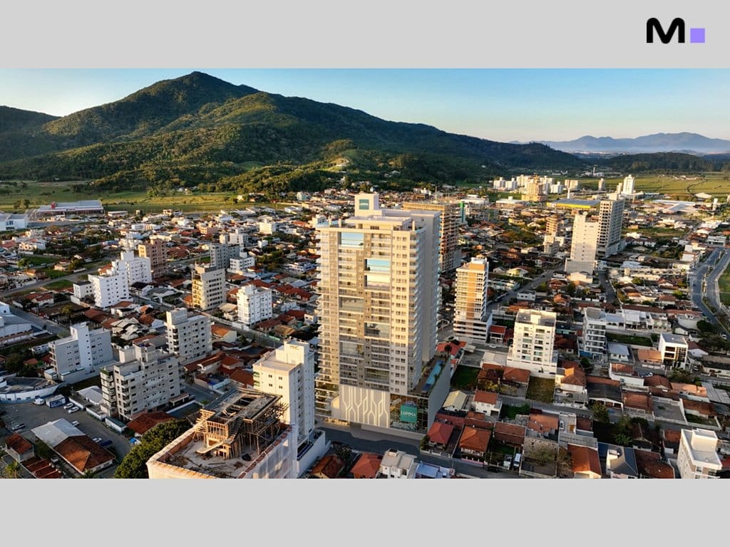 Vista aérea do Seven Residence, um edifício alto em meio a uma cidade com montanhas ao fundo.